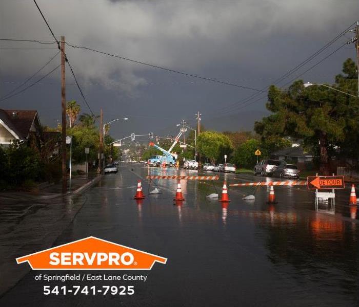 Downed powerlines and flooding dominate the view of a street after a storm has passed.
