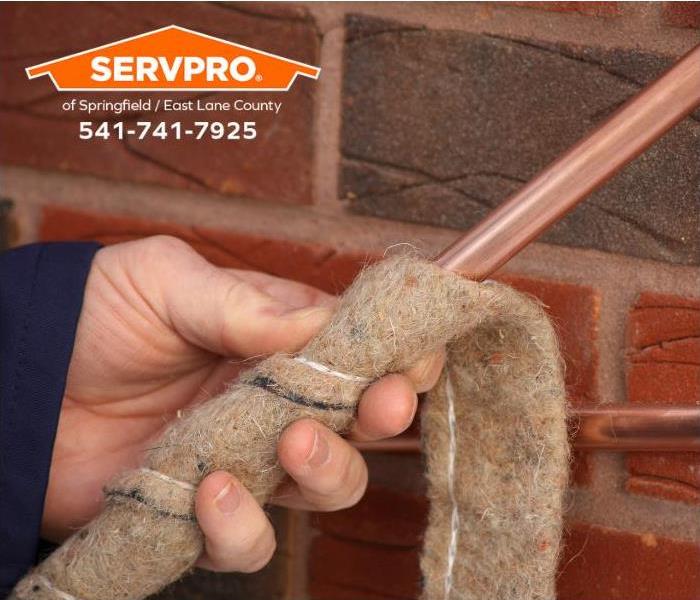 A person wraps a copper pipe with insulation to prevent it from freezing.