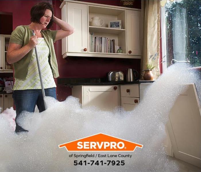 A person watches as the dishwasher malfunctions and floods the floor with soap suds.